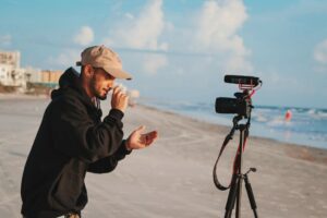 A man sets up a camera for vlogging at the beach.