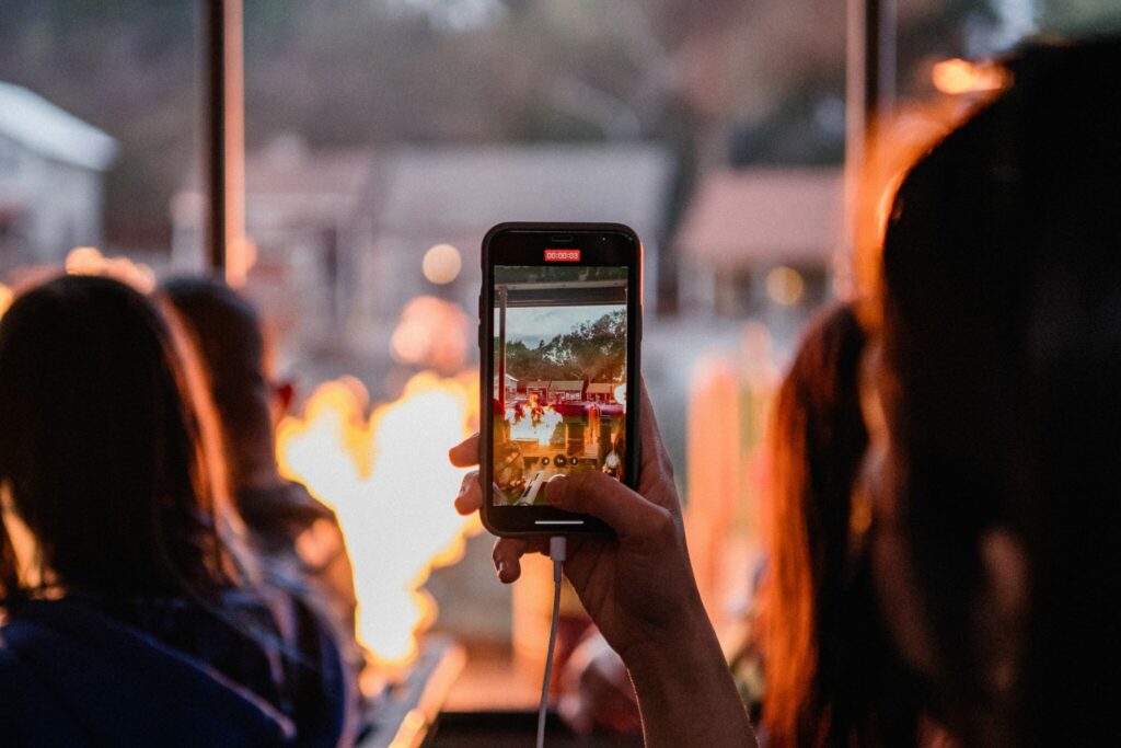A closeup of someone holding a phone recording a bonfire.