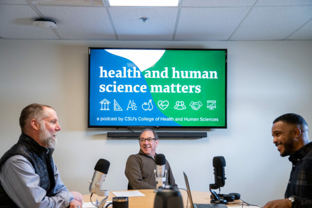 Matt Hickey, Rick Miranda, and Avery Martin sitting at a table during a podcast recording. On the T V screen behind them is a graphic that says health and human science matters.